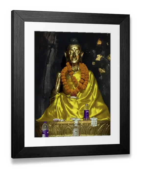 Framed Print : Gilded Buddha statue with flower garland in dark surroundings