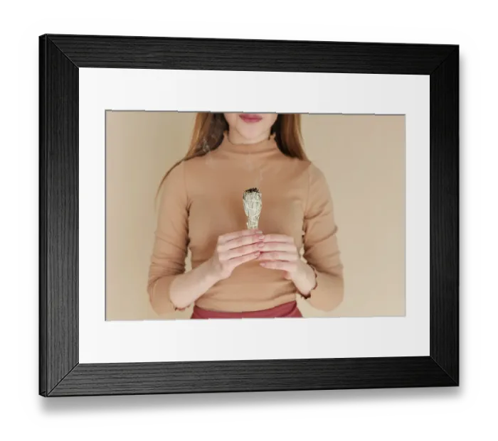 Framed Print : Unrecognizable female burning sage smudge stick and smelling smoke against beige wall during meditation