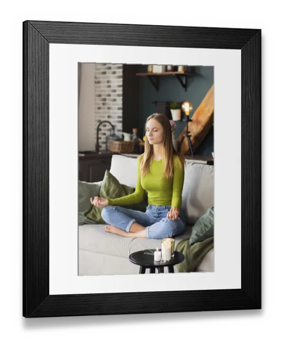 Framed Print : barefoot woman sitting on sofa in Lotus pose and meditating during yoga session at home