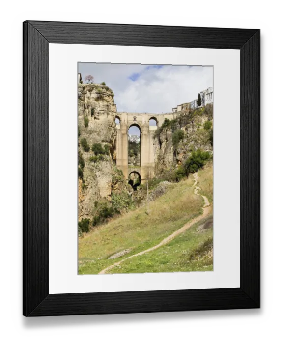 Framed Print : Footpath through a meadow leading to the New Bridge (Spanish: Puente Nuevo) from 18th century in the town of Ronda