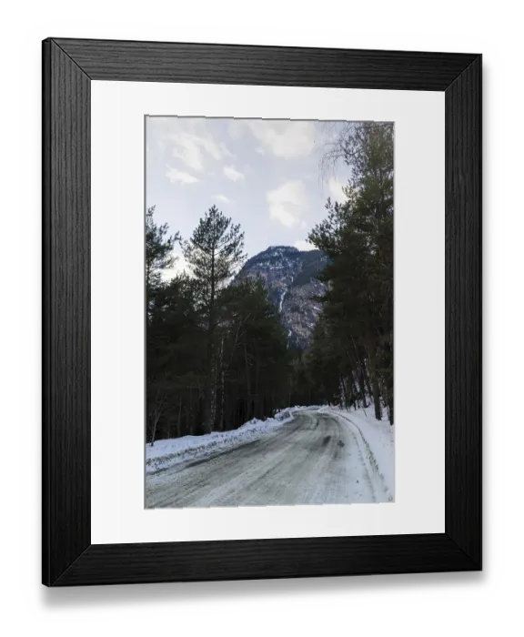 Framed Print : A view of a winter mountain road covered with snow and sand in a pine forest Framed Print : A view of a winter mountain road covered with snow and sand in a pine forest