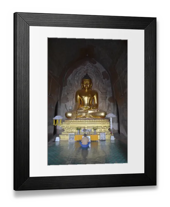 Framed Print : Burmese man sitting, praying in front of a golden Buddha statue