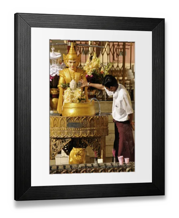 Framed Print : Man pouring water over a Buddha statue