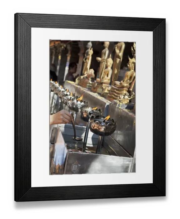 Framed Print : A hand pouring oil to burn in lotus-shaped metal bowls Framed Print : A hand pouring oil to burn in lotus-shaped metal bowls
