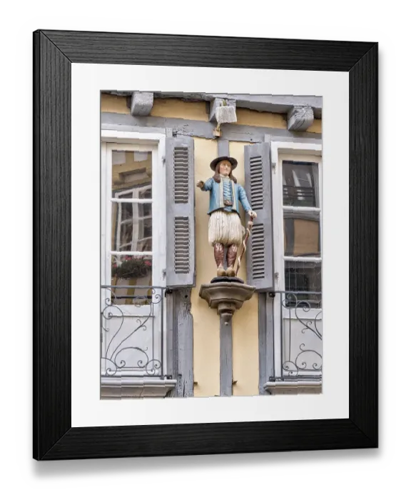 Framed Print : Detail of the half-timbered house with statue of a man in historical traditional costume in the Rue Kereon