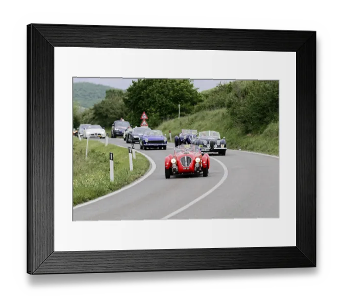 Framed Print : Several classic cars in a convoy drive on a winding country road through a green landscape