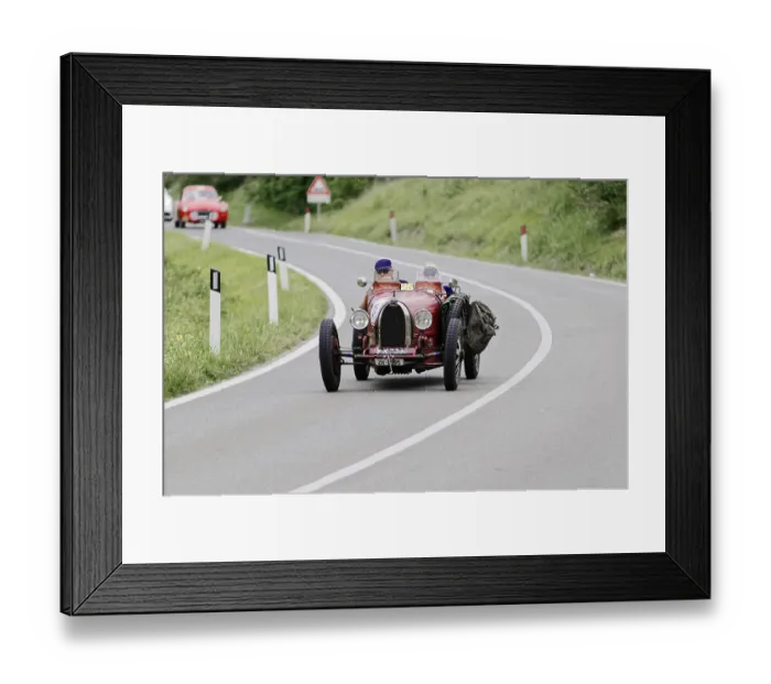 Framed Print : A red, vintage racing car drives along a winding country road Framed Print : A red, vintage racing car drives along a winding country road