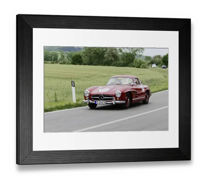 Framed Print : Red Mercedes vintage car on country road with green landscape