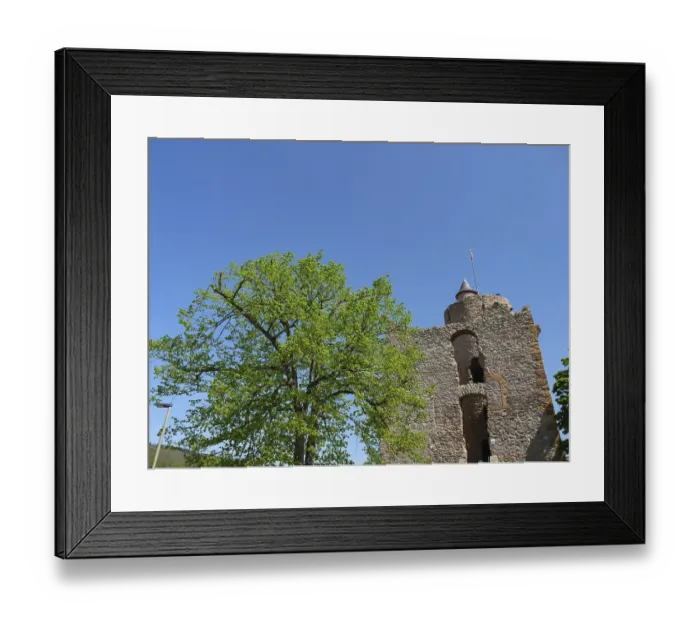 Framed Print : Stone castle tower surrounded by green trees and a clear blue sky on a sunny day
