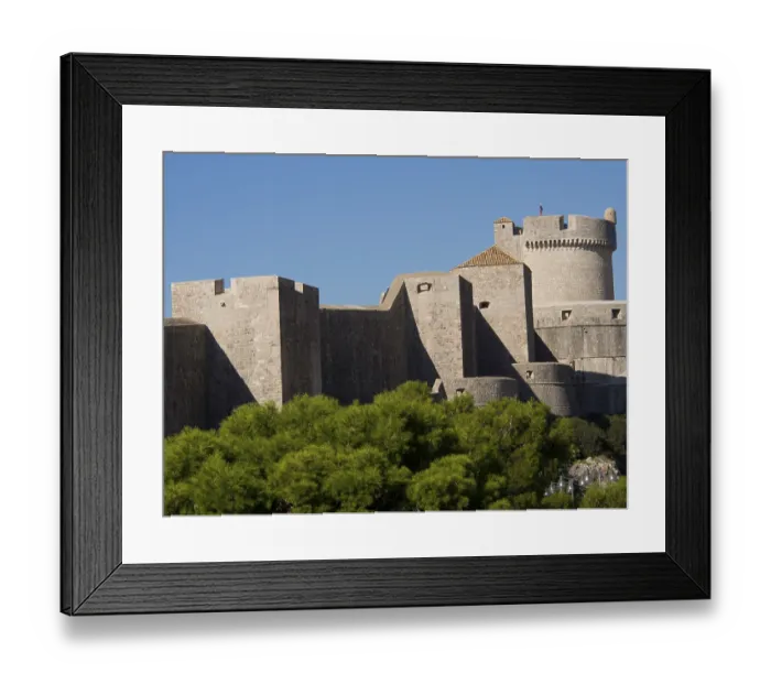 Framed Print : An imposing medieval fortress with high walls and towers rises into the blue sky