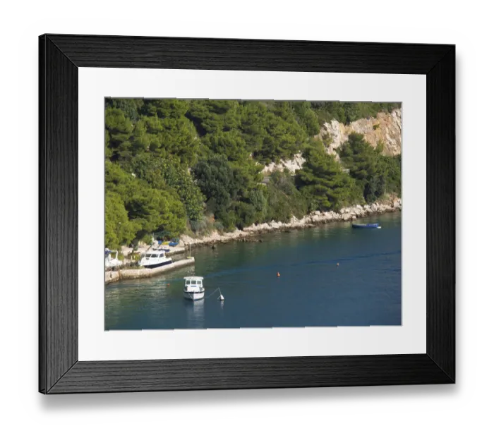 Framed Print : Coast with small boats and dense green vegetation along a rocky shore Framed Print : Coast with small boats and dense green vegetation along a rocky shore