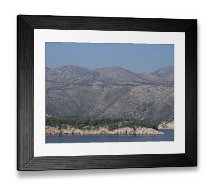 Framed Print : Green coastal landscape with mountains in the background and calm sea in the foreground