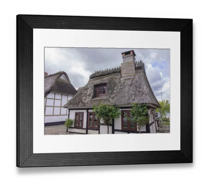Framed Print : Half-timbered houses with thatched roofs and chimneys in cobbled street environment and cloudy sky Framed Print : Half-timbered houses with thatched roofs and chimneys in cobbled street environment and cloudy sky