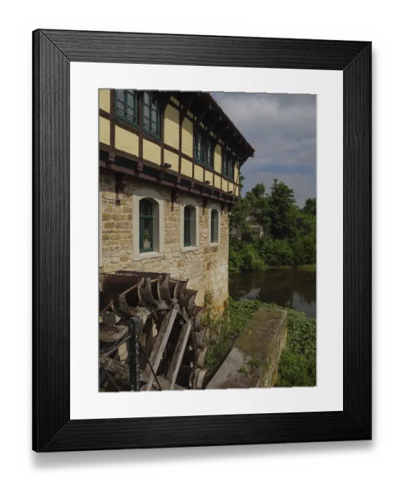 Framed Print : Historic half-timbered house with a large water wheel and river in the background Framed Print : Historic half-timbered house with a large water wheel and river in the background