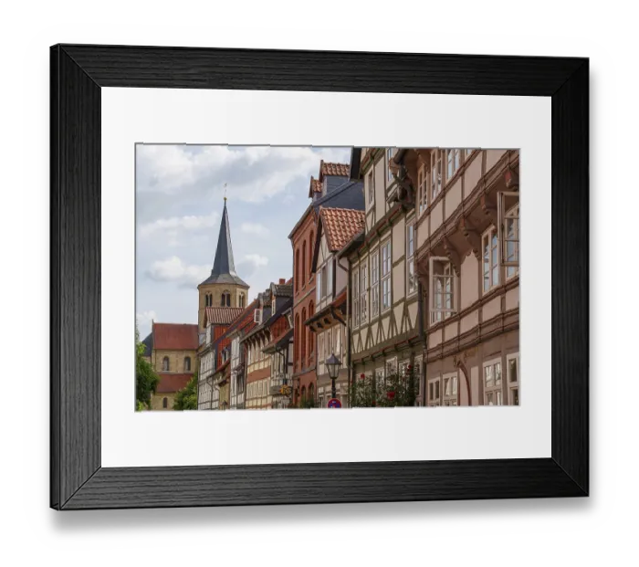 Framed Print : Street with half-timbered houses and church tower on the horizon