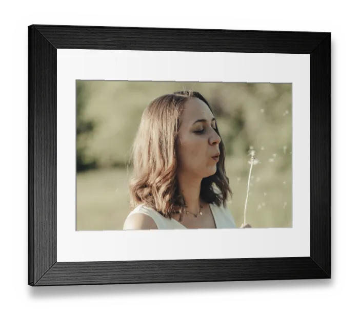 Framed Print : Woman in a garden blows away a dandelion Framed Print : Woman in a garden blows away a dandelion