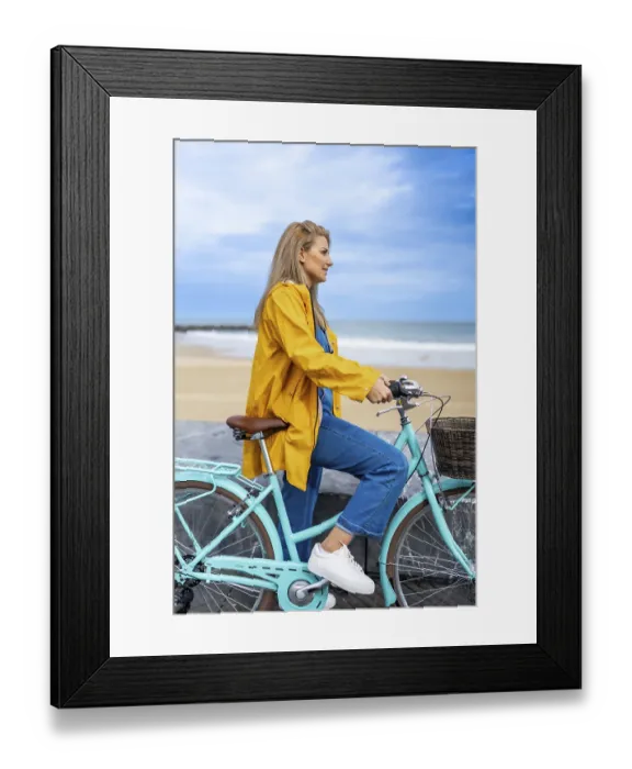 Framed Print : Young woman wearing yellow raincoat sitting on her light blue bicycle
