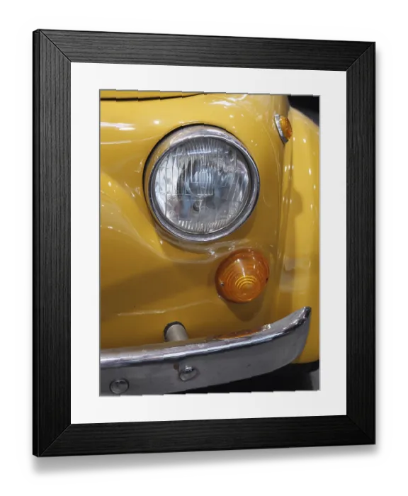 Framed Print : Close-up of a yellow vintage car front end with round headlight and indicators