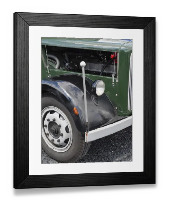 Framed Print : Front part of a vintage car with visible wheel and mechanical details