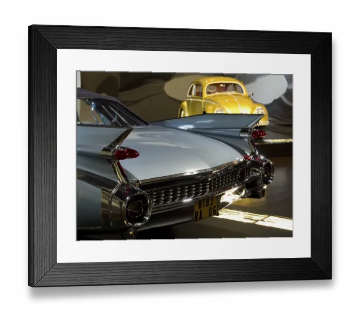 Framed Print : Cadillac with fins and yellow VW Beetle in the background in an exhibition