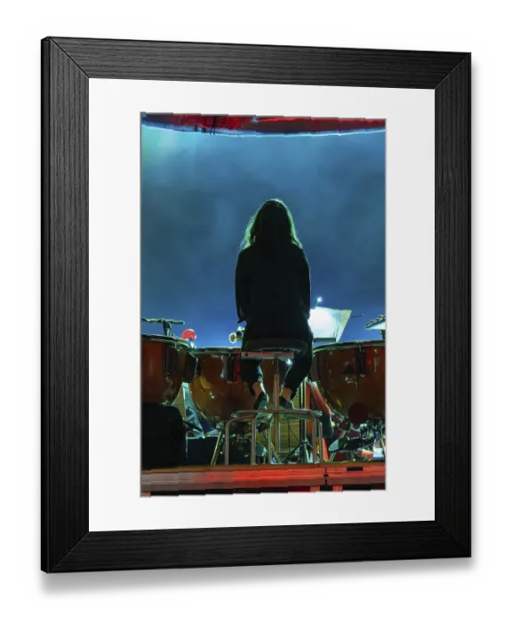 Framed Print : Back view of a musician playing drums on a darkly lit stage