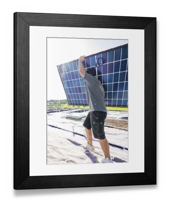 Framed Print : Worker carrying a solar panel on a roof under bright sunshine Framed Print : Worker carrying a solar panel on a roof under bright sunshine