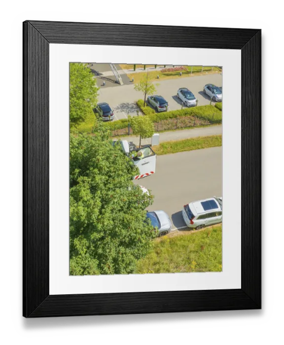 Framed Print : Aerial view of a car park next to a road with trees