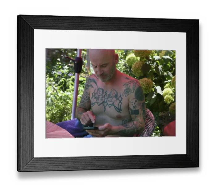 Framed Print : Young man on mobile phone, with tattoos on arms and upper body