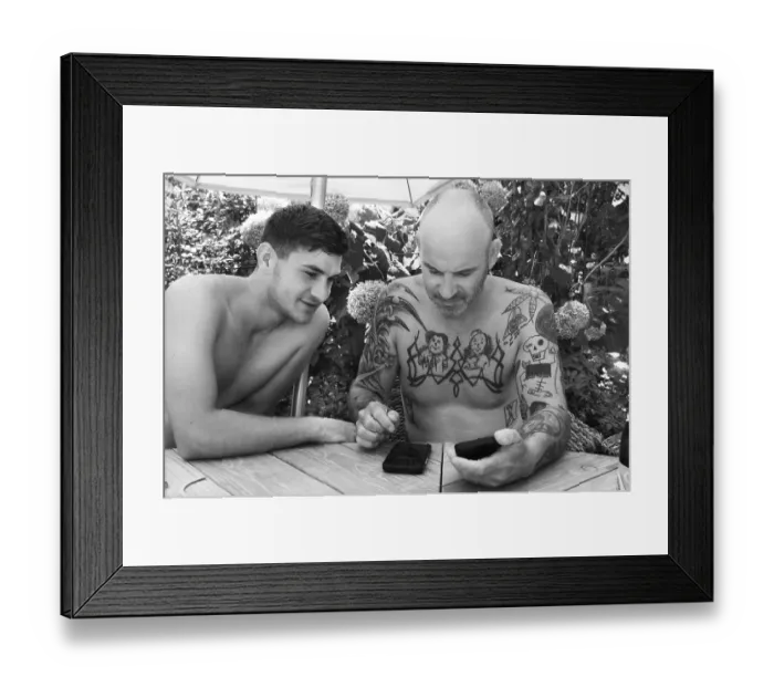 Framed Print : Father and son in garden on mobile phone