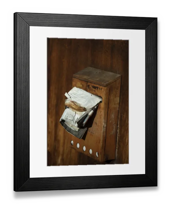 Framed Print : A rusty mailbox attached to a weathered wall is bursting with various papers and ads