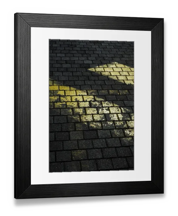 Framed Print : Faded yellow markings on dark, textured stone pavement create a striking contrast