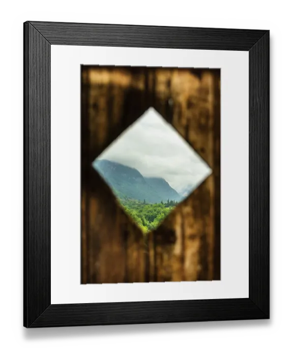 Framed Print : Rustic wooden frame reveals a lush green landscape with mountains in the background under a cloudy sky Framed Print : Rustic wooden frame reveals a lush green landscape with mountains in the background under a cloudy sky