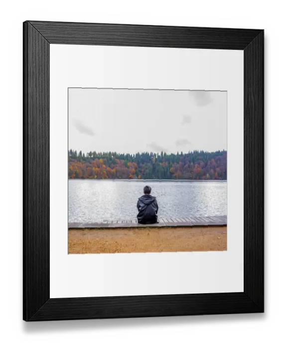 Framed Print : A solitary figure sits on a wooden dock Framed Print : A solitary figure sits on a wooden dock