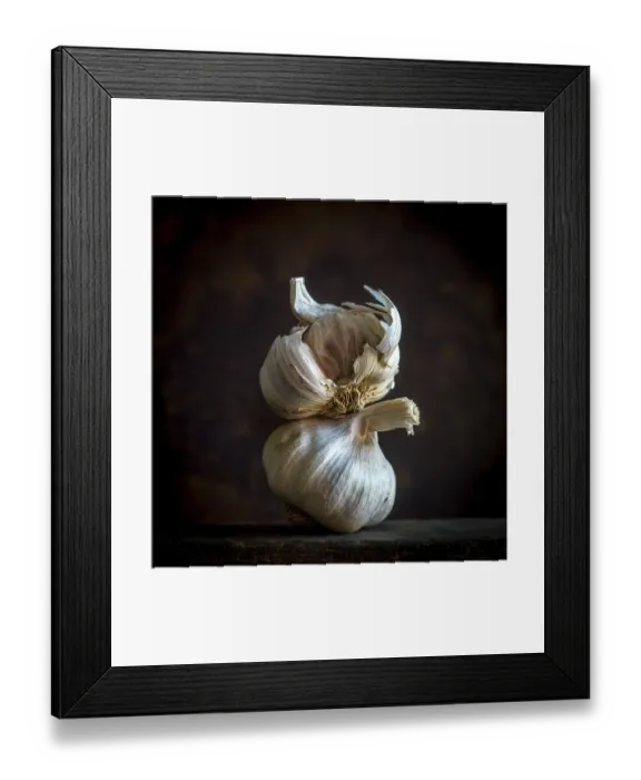 Framed Print : Garlic cloves are arranged carefully against a black background