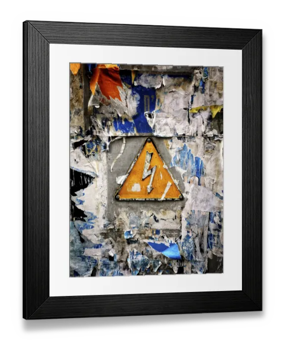 Framed Print : A bright yellow warning sign featuring a lightning bolt is mounted on a wall heavily covered with faded Framed Print : A bright yellow warning sign featuring a lightning bolt is mounted on a wall heavily covered with faded