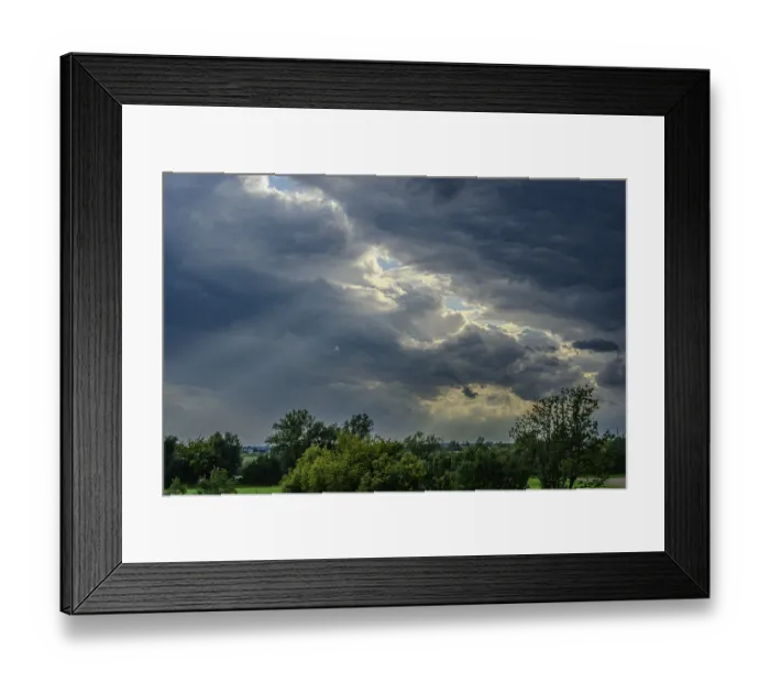 Framed Print : Thick, grey clouds cover the sky over a green landscape