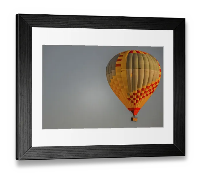 Framed Print : A colourful hot-air balloon floats gently through the clear sky as the sun slowly sets on the horizon Framed Print : A colourful hot-air balloon floats gently through the clear sky as the sun slowly sets on the horizon