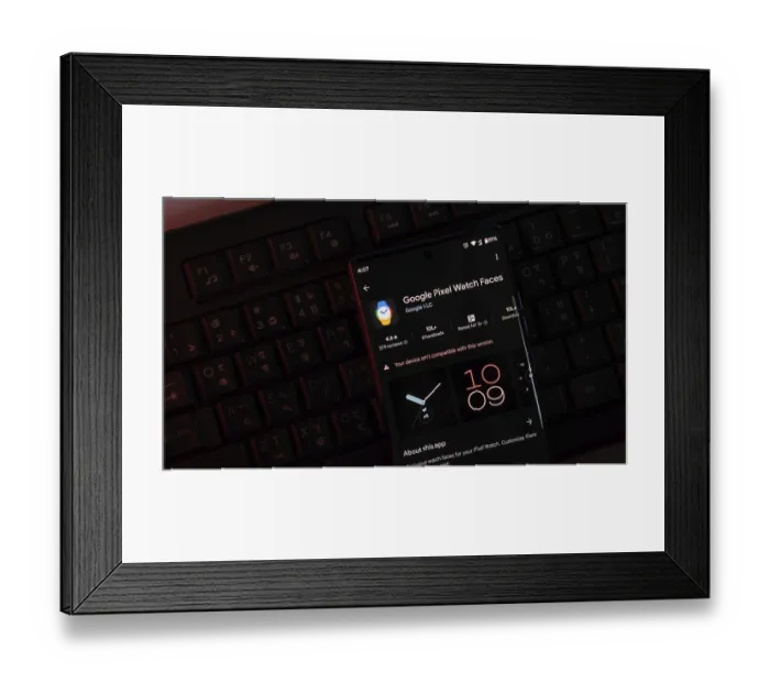 Framed Print : Google Pixel Watch Faces app displayed on a phone screen with a dark-themed keyboard background Framed Print : Google Pixel Watch Faces app displayed on a phone screen with a dark-themed keyboard background