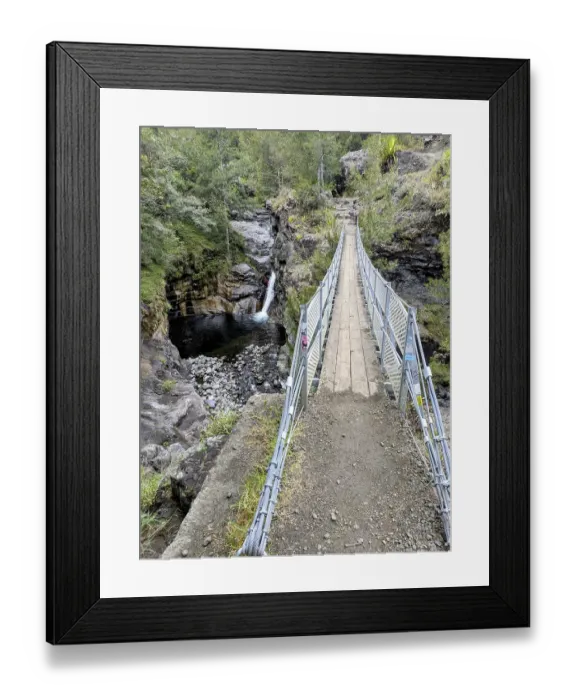 Framed Print : Metal footbridge crossing above a small waterfall in a rocky forested area