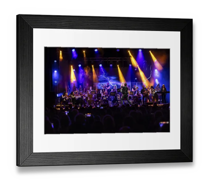 Framed Print : An orchestra plays on an illuminated stage in front of a large audience
