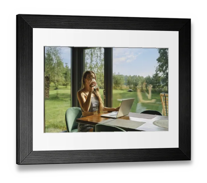 Framed Print : Woman working at bungalow in the woods on weekend and sipping mineral water from a glass