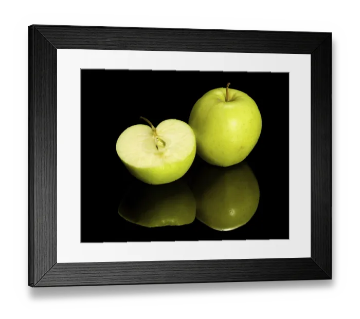 Framed Print : Green apple and halved on dark reflective ground