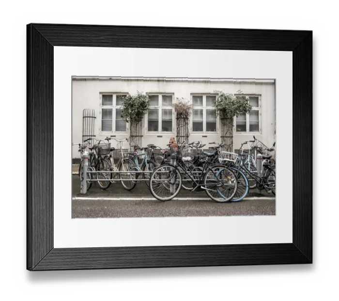 Framed Print : Bicycles lined up against a building facade with white windows on an urban street