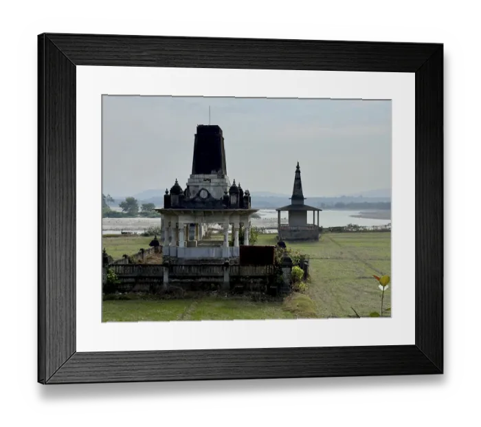 Framed Print : An ancient temple by a river in a rural landscape with a cloudy sky in the background