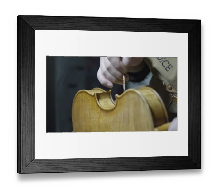 Framed Print : A hand is working on a violin, highlighting craftsmanship and wooden texture Framed Print : A hand is working on a violin, highlighting craftsmanship and wooden texture