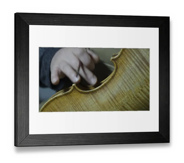 Framed Print : Close-up of a hand working on the intricate details of a violin
