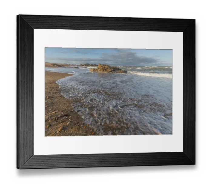 Framed Print : A wide sandy beach stretches out with scattered pebbles and beach shells Framed Print : A wide sandy beach stretches out with scattered pebbles and beach shells