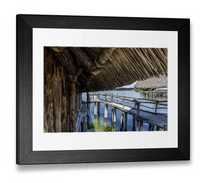 Framed Print : Rustic wooden path under a thatched roof with a view of the water