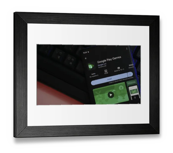 Framed Print : Smartphone displaying Google Play Games app installation page with a keyboard backdrop