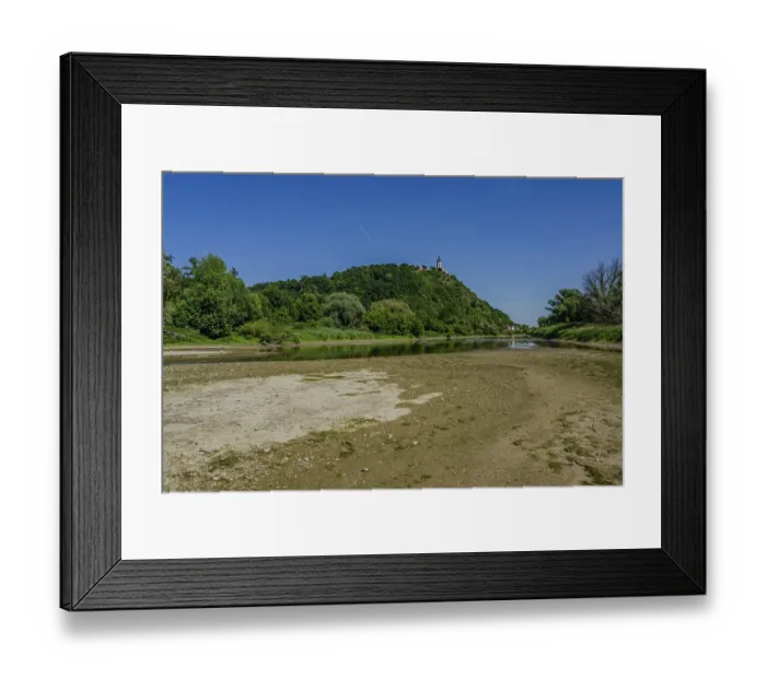Framed Print : A gentle river flowing by a wooded hill with a clear sky and sunny weather in the background
